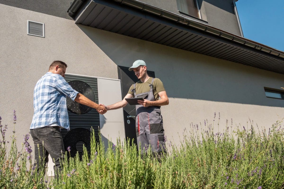 Two men shaking hands in front of a building.
